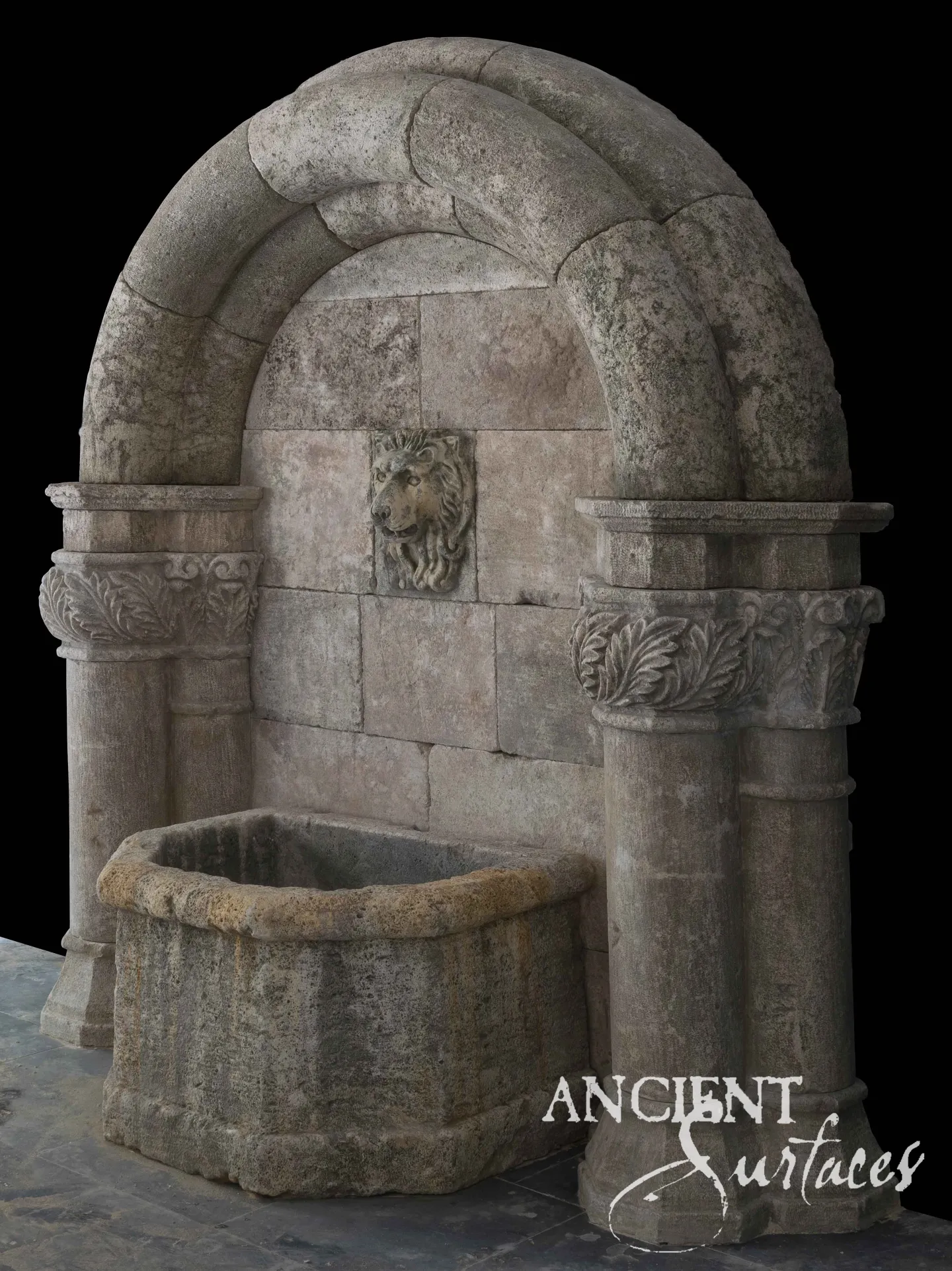 Arched antique limestone wall fountain on columns with a carved lion's-head spout and stone trough